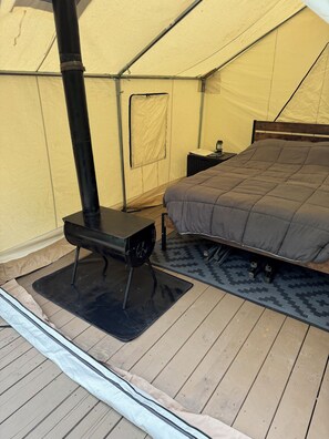 A tent with a bed, a table, and a portable heater.