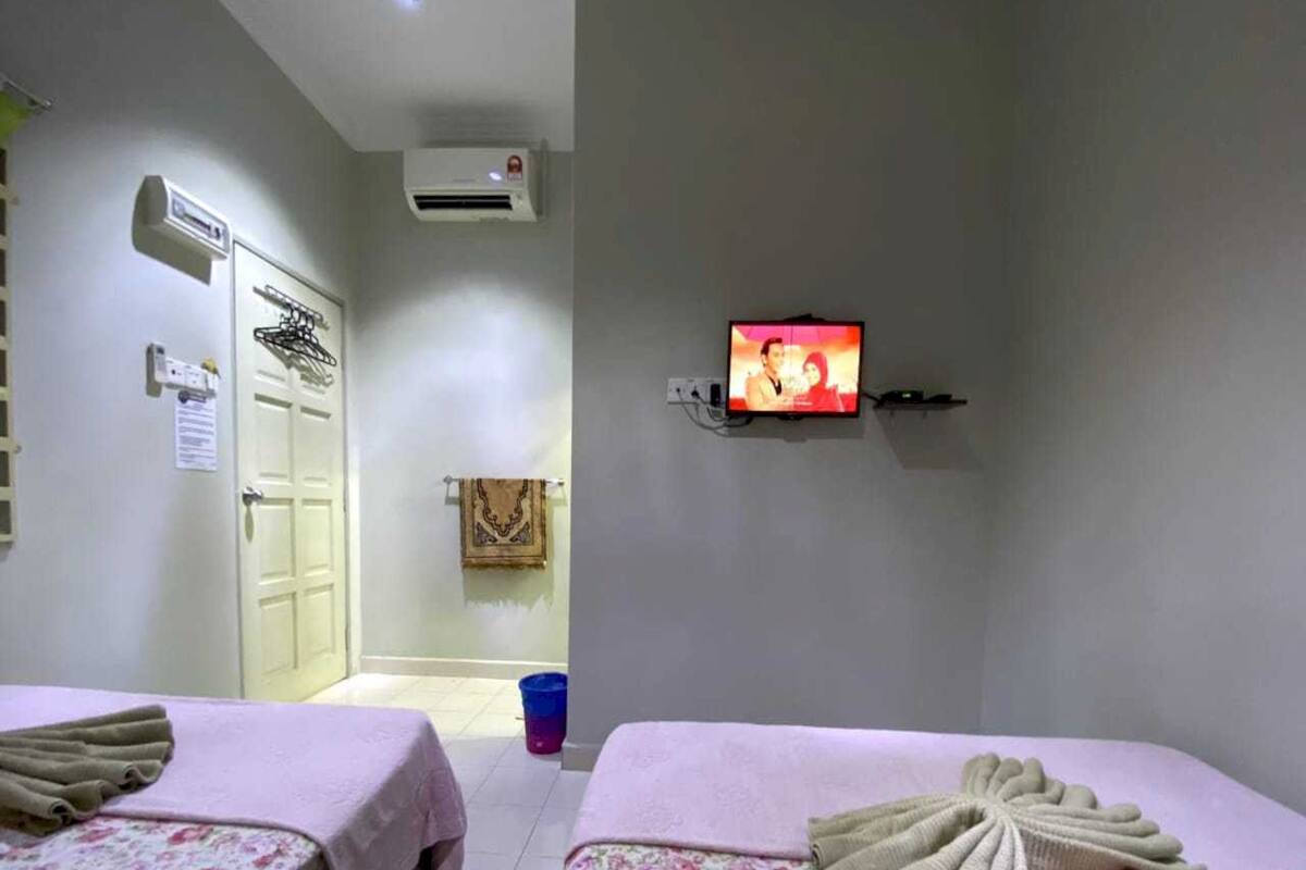 Ein Hotelzimmer mit zwei Betten, einem Fernseher, einer Klimaanlage und einem durch eine offene Tür einsehbaren Badezimmer.