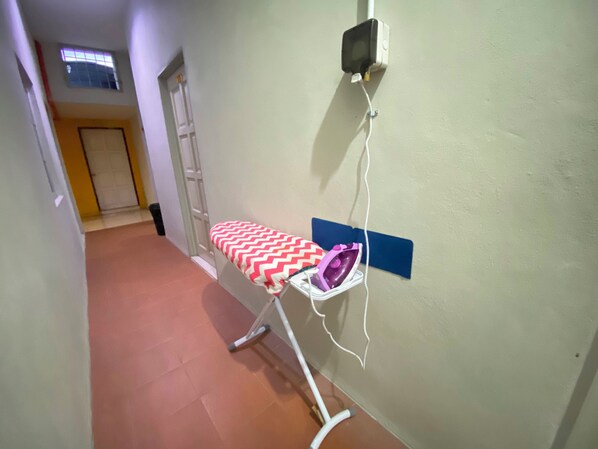 A hallway with a wall-mounted ironing board and an iron. - Hotel O D Qamar Motel (Langkawi)