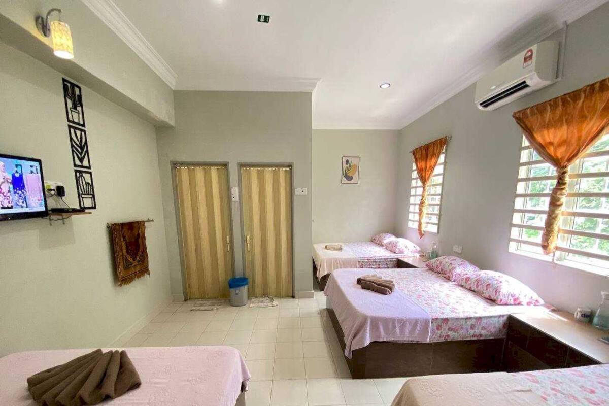 Ein Hotelzimmer mit drei Betten, einem Fernseher und einem fenster mit Vorhängen.