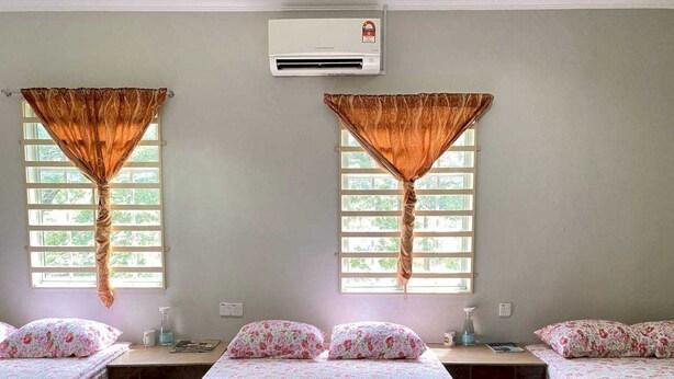 A hotel room with two beds, a large window with curtains, an air conditioning unit, and a bedside table with a lamp. - Hotel O D Qamar Motel (Langkawi)