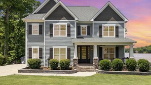 A two-story house with a front porch, a stone foundation, and a view of a lake. - Peaceful Lake Wylie Waterfront Home in Belmont. Great Views, Beautiful interiors (Belmont)
