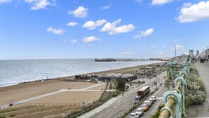 A coastal road with a beach and a pier in the background. - The Cheeky Chappie By My Getaways (Brighton)