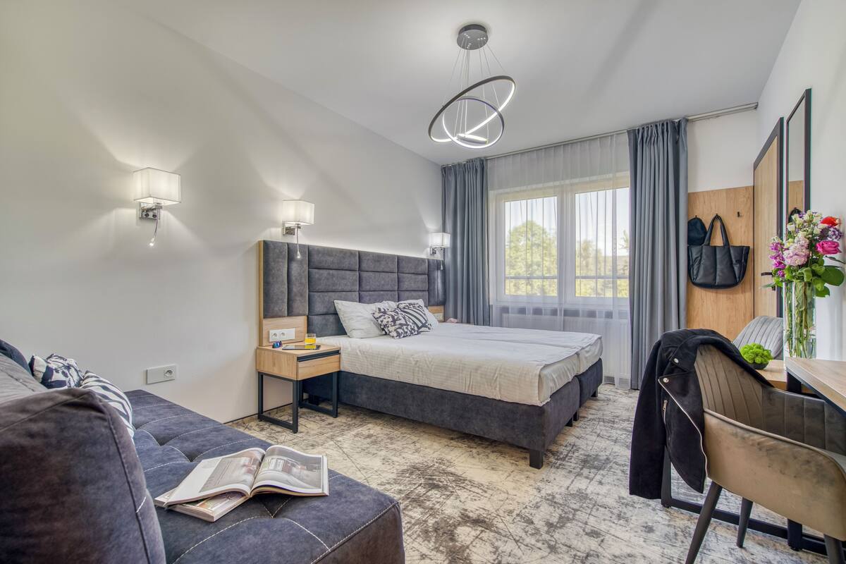 A modern bedroom with a large bed, bedside tables, a reading chair, and a desk.