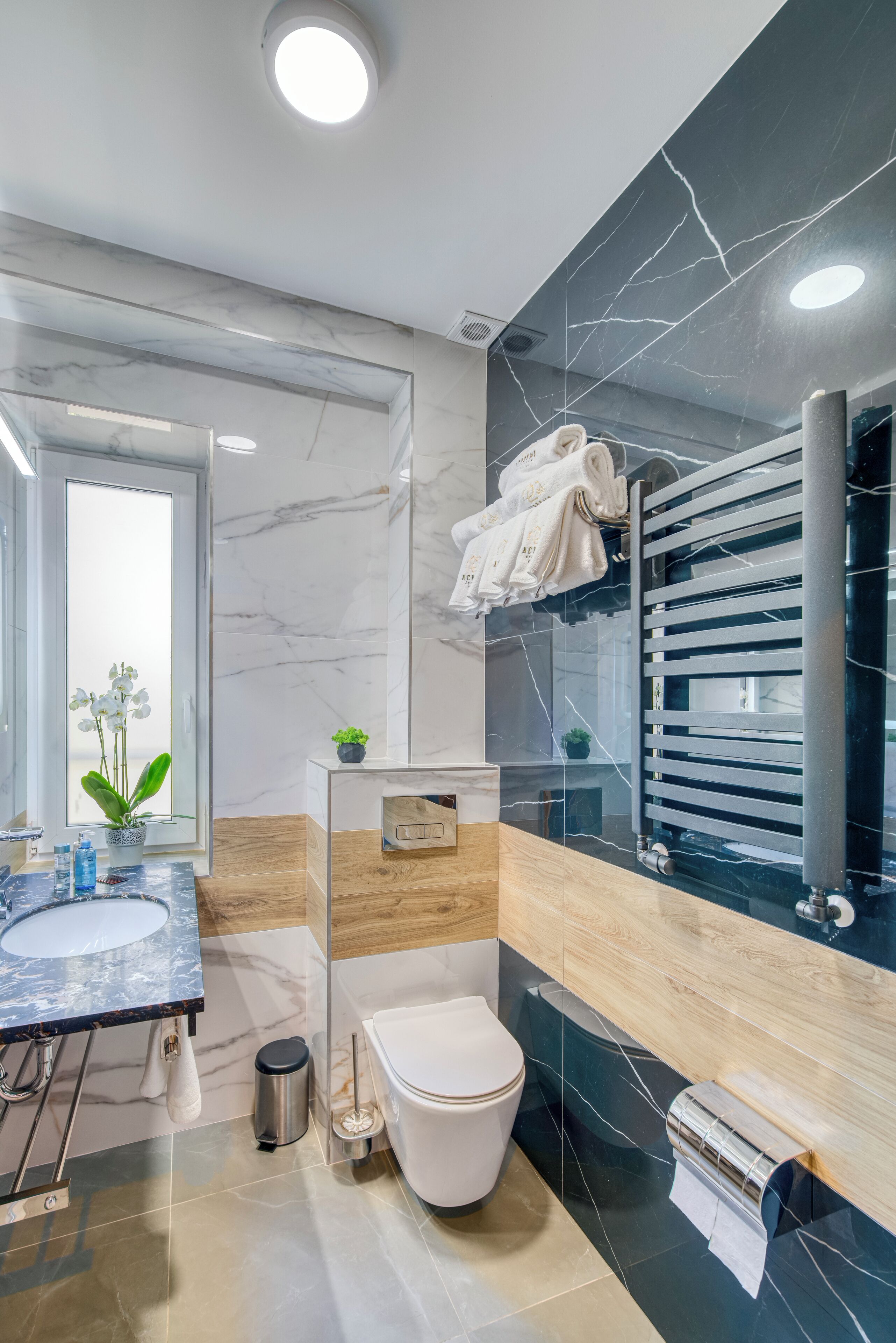 A modern bathroom with a marble vanity, a toilet, and a towel rack.