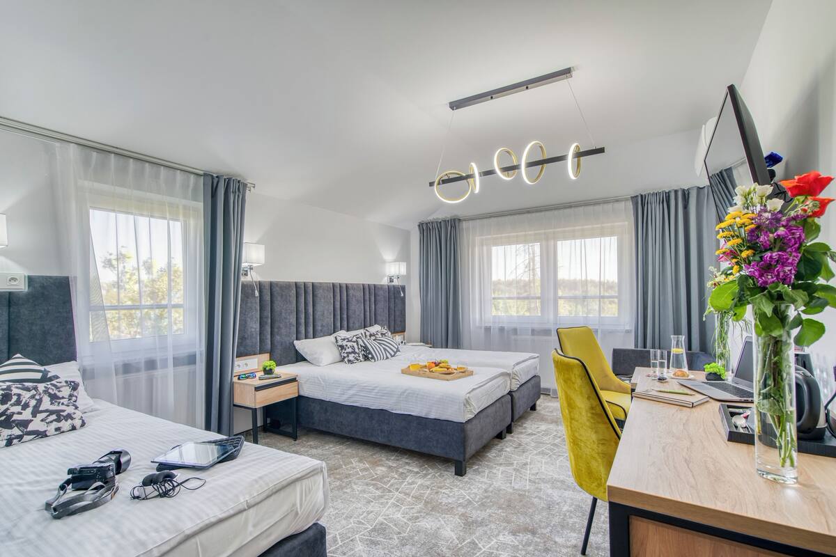 A modern hotel room with a bed, a desk, a chair, and a large window.
