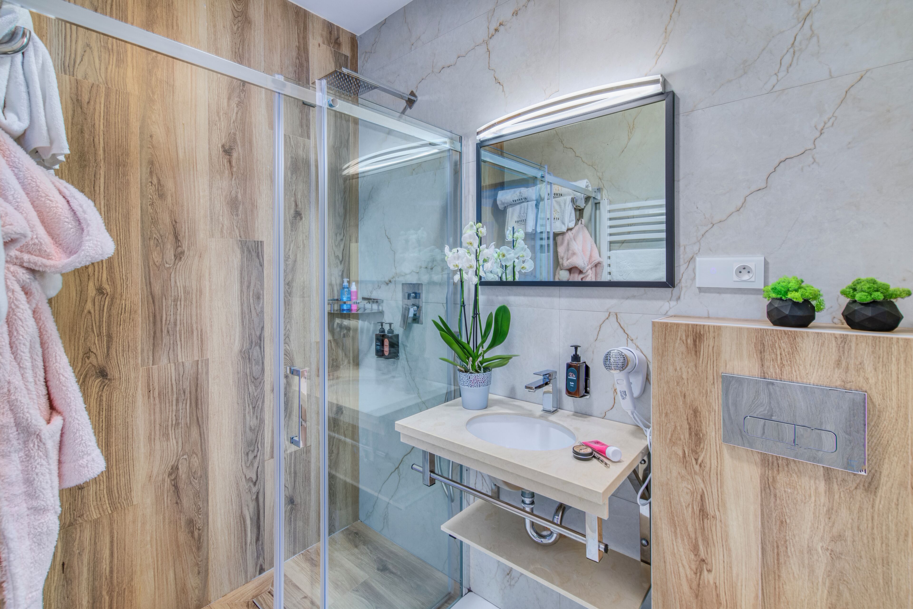 Une salle de bain moderne avec une douche à parois de verre, un meuble-lavabo en bois et un miroir au-dessus du meuble.
