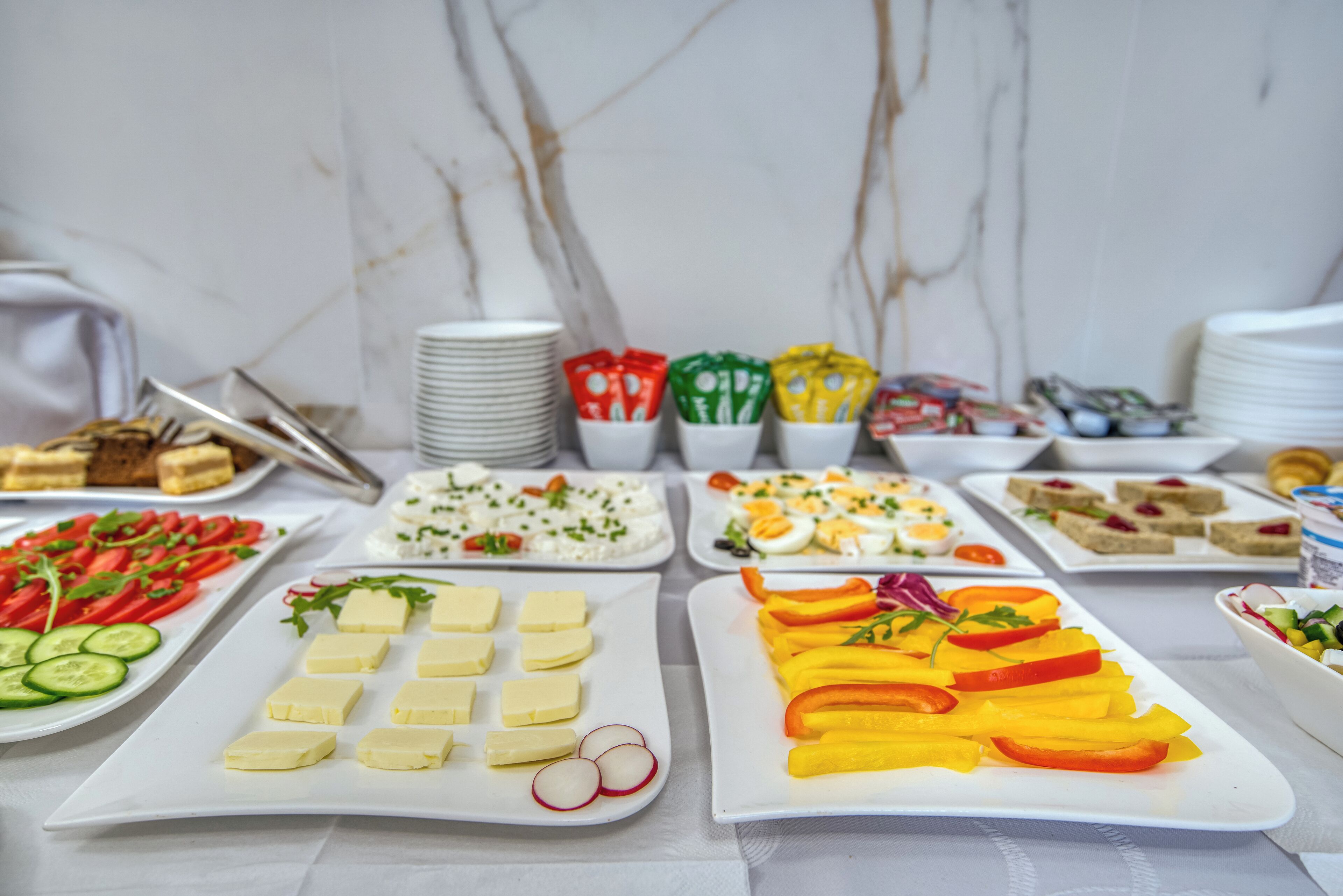 A buffet table with various food items including salads, cheeses, and sandwiches.