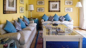 A living room with two sofas, a glass coffee table, and framed pictures on the wall.