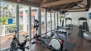 A gym with cardio equipment, weight machines, and a view of a residential area.
