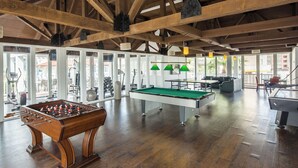 A spacious indoor area with a foosball table, pool table, and exercise equipment.