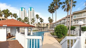 A resort pool area with a wooden deck, a small pool, and palm trees.