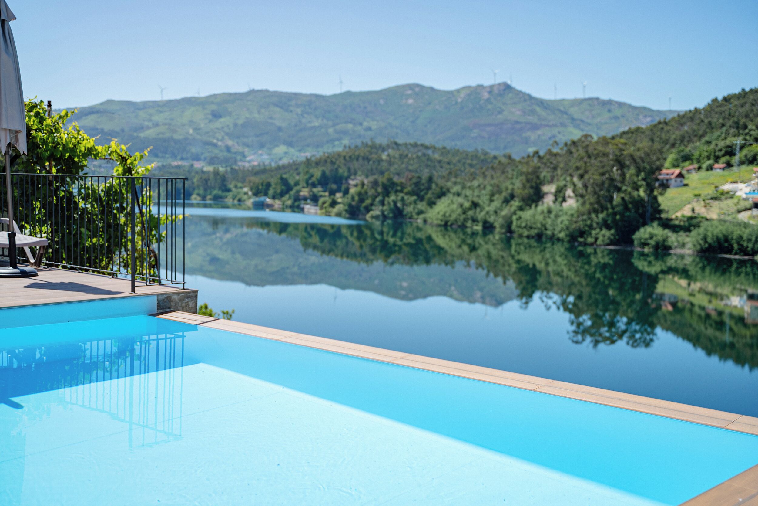 A clear swimming pool with a view of a lake and mountains in the background.
