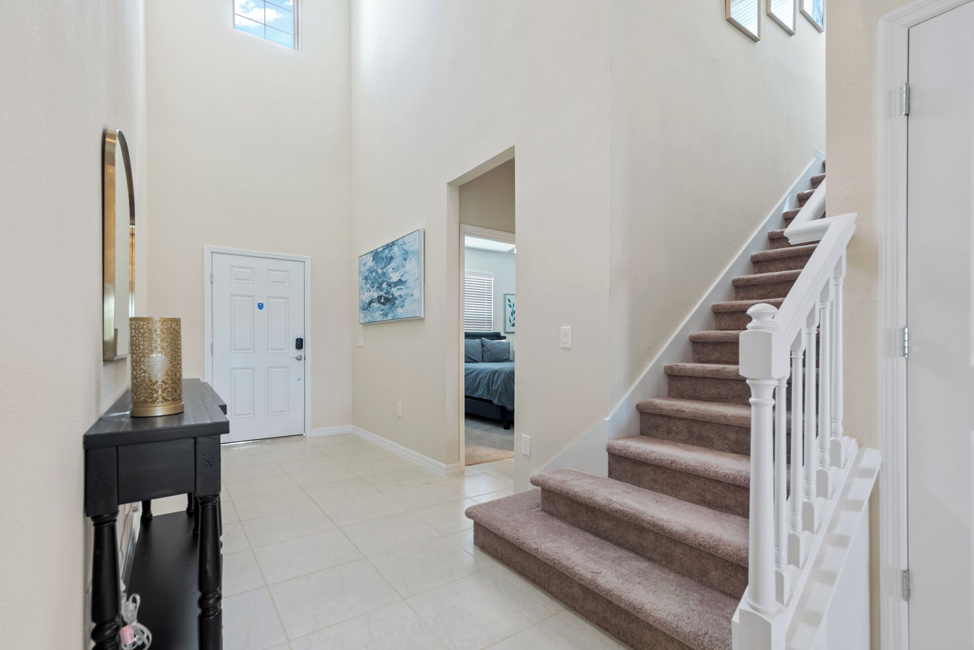 A hallway with a staircase, a door, a framed artwork, and a decorative vase.