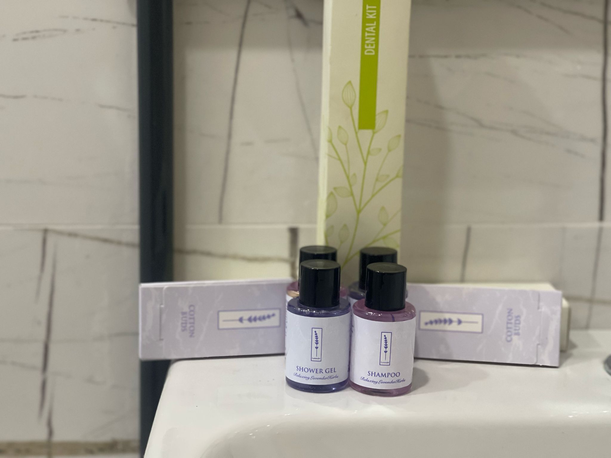 A bathroom with a white sink, two bottles of lavender-scented hair products, and a green vertical sign above the sink.