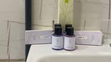 A bathroom with a white sink, two bottles of lavender-scented hair products, and a green vertical sign above the sink.