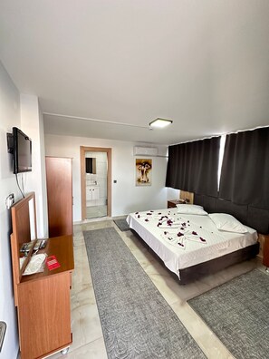 Una camera d'albergo con un letto, una scrivania con un computer, un condizionatore d'aria e una televisione.
