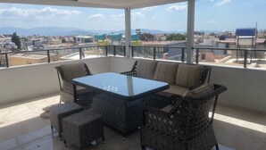 A covered outdoor seating area with a table and chairs, a view of the cityscape, and an exit sign. - Aristo2 Butik Otel (Didim)