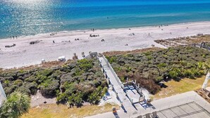 A beach with a wooden walkway leading to a viewing platform, overlooking the sea.