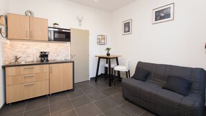 A compact living space with a kitchenette, a sofa, and a small table with chairs. - Studio Quiet Downtown Rieumes (Rieumes)
