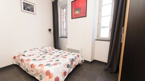 A bedroom with a bed, a window, and a door. - Studio Quiet Downtown Rieumes (Rieumes)