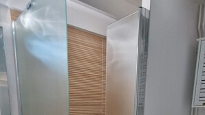 A modern bathroom with a glass shower enclosure, a wooden vanity, and a toilet.