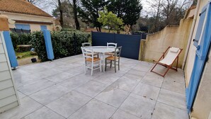 A patio with a white table and chairs, a blue fence, and a beige wall.