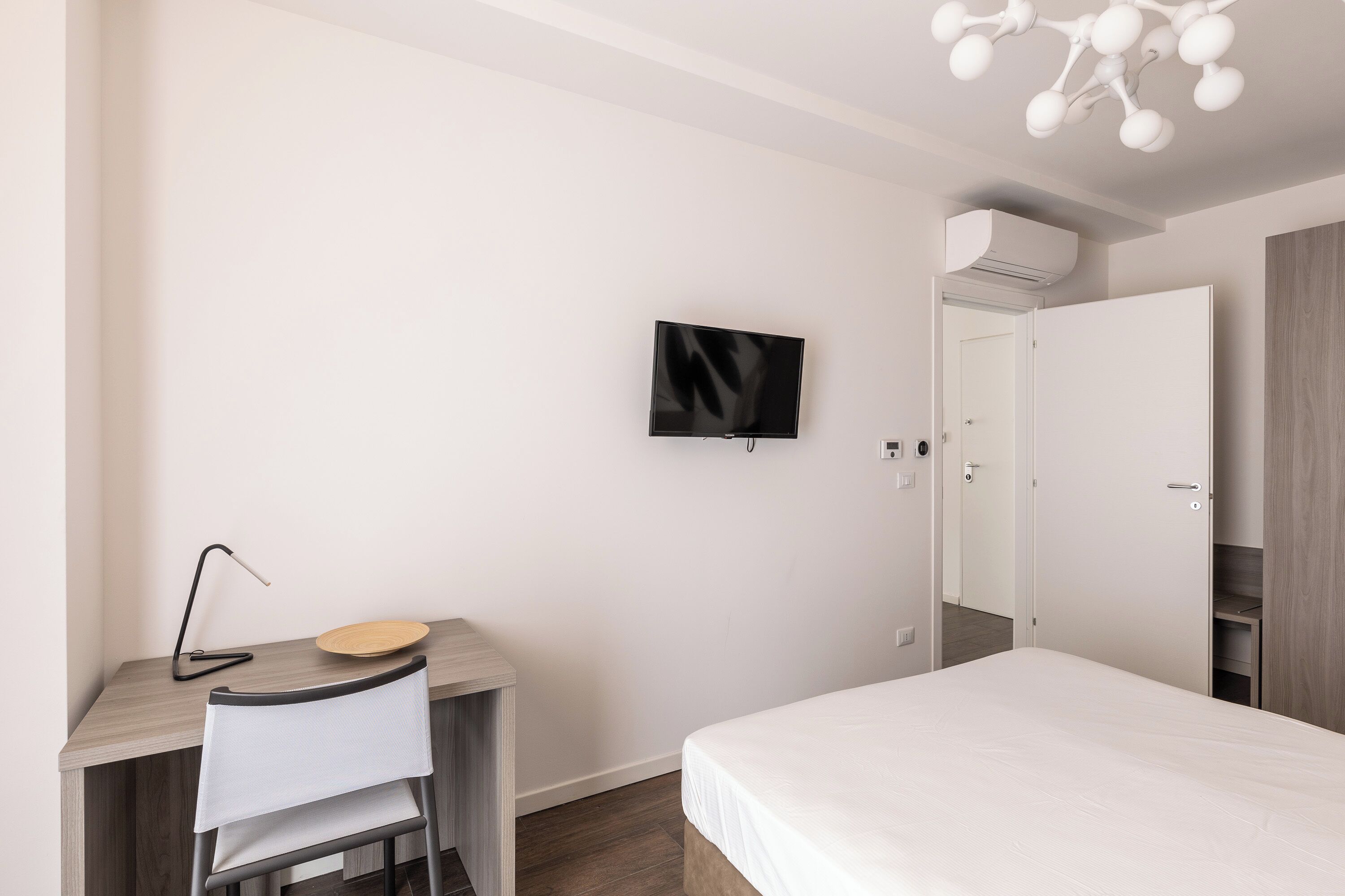 Una camera da letto con un letto, una scrivania con una sedia, una televisione e un armadio.