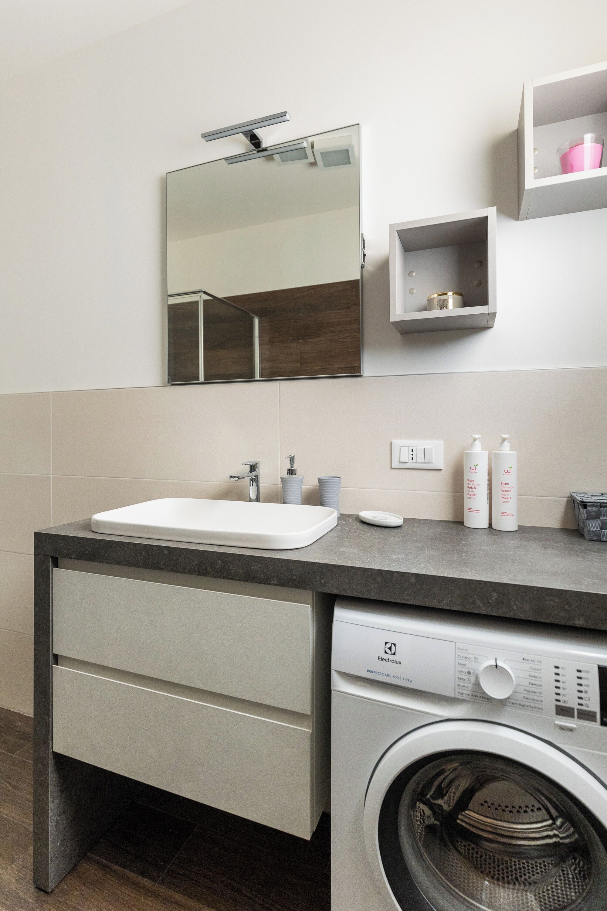A modern bathroom with a sink, mirror, and a washing machine.