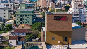 Un edificio de gran altura con el logotipo 'G/V' bien visible en su fachada, rodeado de otros edificios y vistas al mar.