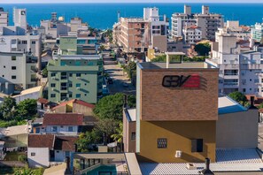 Un edificio de gran altura con el logotipo 'G/V' bien visible en su fachada, rodeado de otros edificios y vistas al mar.