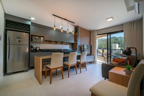 A modern kitchen with a dining area, large windows, and a view of the outdoors. - Las Vegas  (Bombinhas)