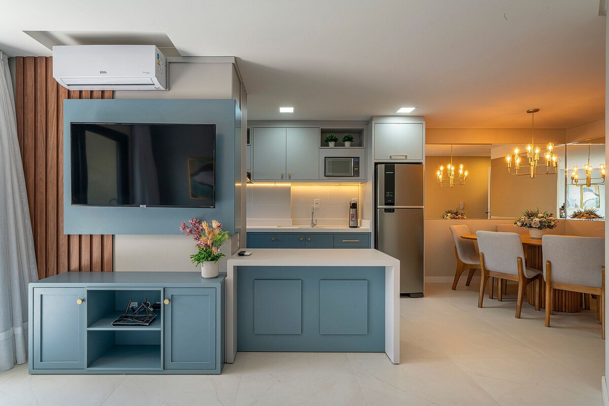 Una cocina moderna con televisión integrada, microondas y refrigerador.