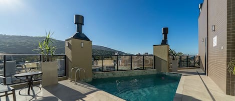 A rooftop pool with a clear view of the cityscape and hills in the background.