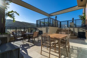 A rooftop terrace with a wooden table and chairs, a glass balustrade, and a view of the surrounding landscape. - Las Vegas  (Bombinhas)