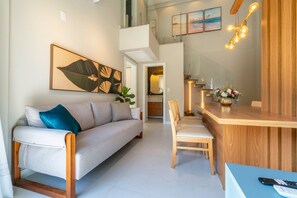 A modern living room with a sofa, a dining table, and a kitchen area. - Las Vegas  (Bombinhas)