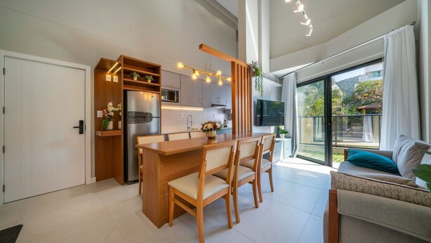 Een moderne keuken met een houten kookeiland, inbouwapparatuur en een grote schuifpui naar een balkon.