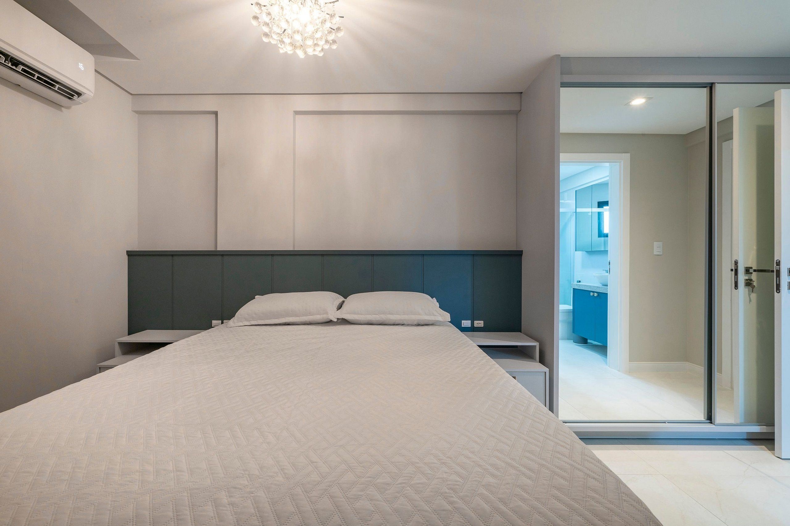 A modern bedroom with a large bed, a headboard, bedside tables, and a ceiling light.