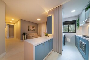 Una cocina moderna con armarios azules, encimera blanca y horno empotrado.