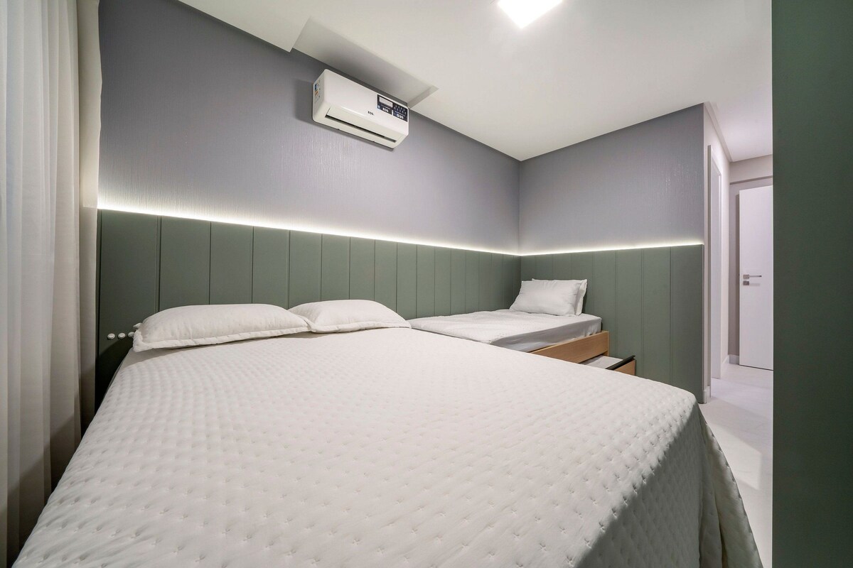 Una habitación de hotel con una cama grande, una cama más pequeña y una mesita de noche.