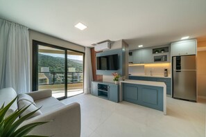 A modern kitchen with a built-in oven, microwave, and refrigerator. There is a large window with a view of the outdoors. - Las Vegas (Bombinhas)
