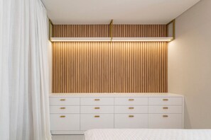 A bedroom with a white bed, a white dresser with gold handles, and a wooden slatted headboard. - Las Vegas  (Bombinhas)