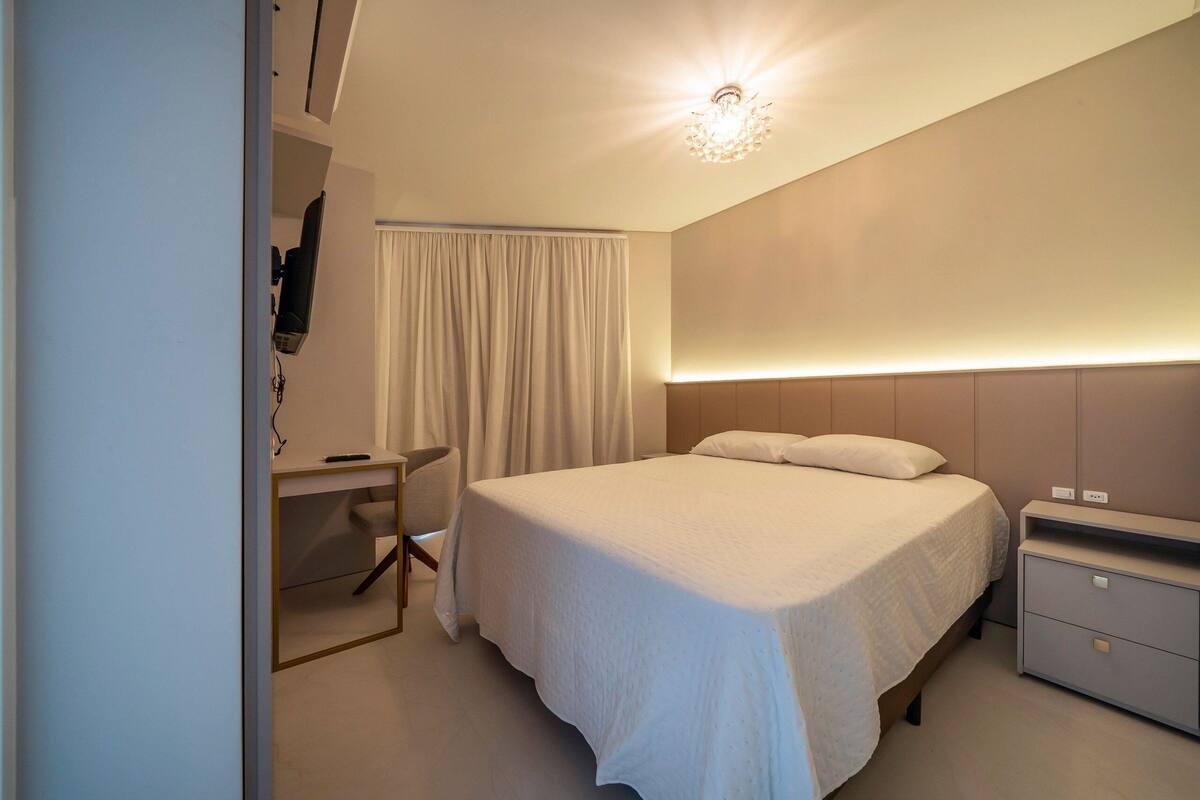 Une chambre à coucher moderne avec un lit, une table de chevet et un bureau avec une chaise.