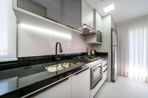 A modern kitchen with a black countertop, stainless steel appliances, and white cabinetry. - Las Vegas  (Bombinhas)