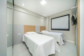 Een hotelkamer met twee bedden, een groot raam en een flatscreen televisie aan de muur.