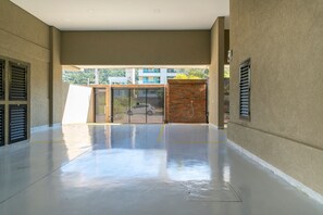 A spacious indoor area with a concrete floor, a metal gate, and a brick wall. - Las Vegas  (Bombinhas)