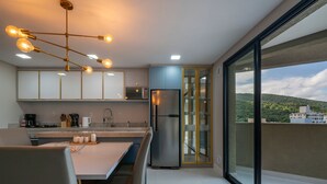 Een moderne keuken met een eethoek, een roestvrijstalen koelkast en uitzicht op een stadsgezicht door grote glazen schuifdeuren.