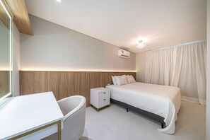 A modern bedroom with a bed, bedside table, and a small nightstand. - Las Vegas  (Bombinhas)