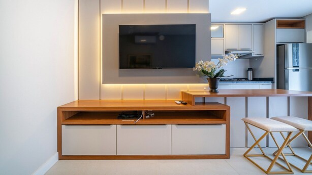 Una cocina moderna con televisor integrado, armarios de madera y una zona de bar.