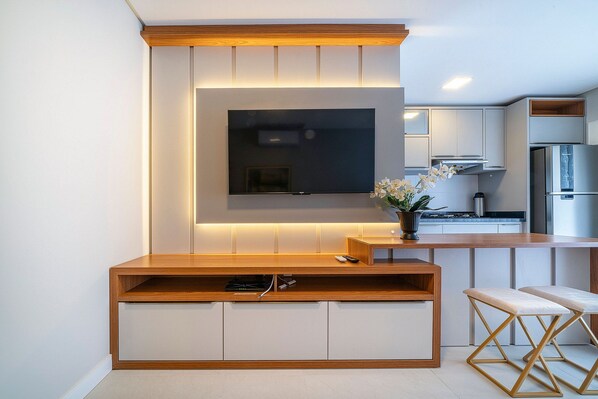 Una cocina moderna con televisor integrado, armarios de madera y una zona de bar.